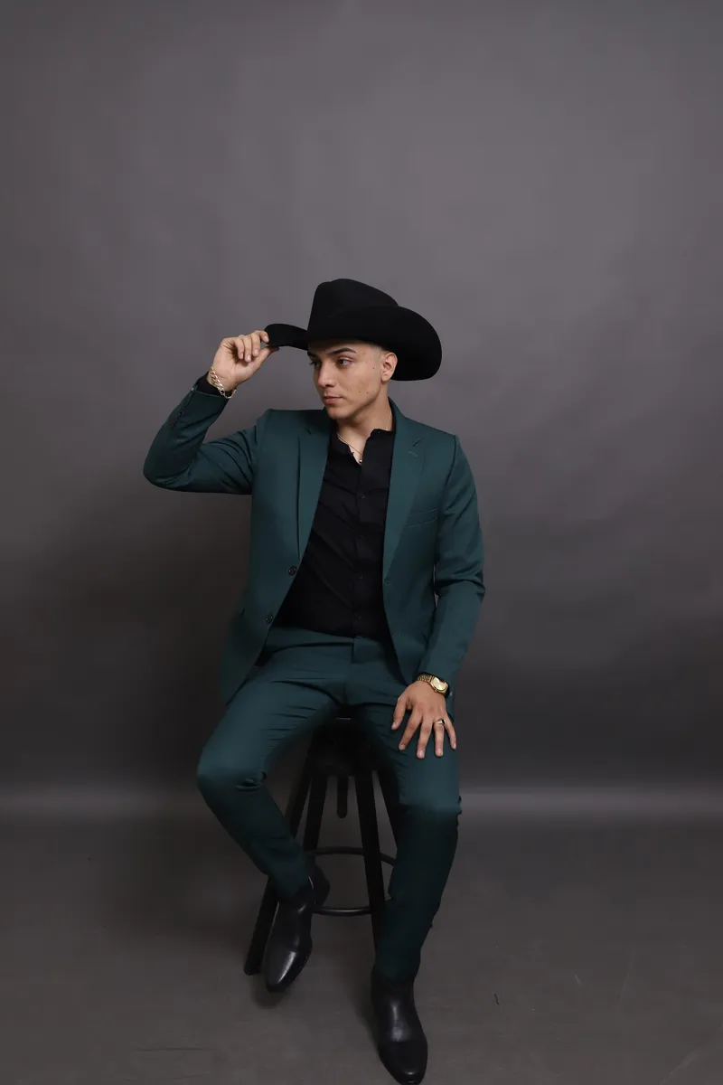 Alonso Guezt sentado, tocando el ala del sombrero y mirando a un lado