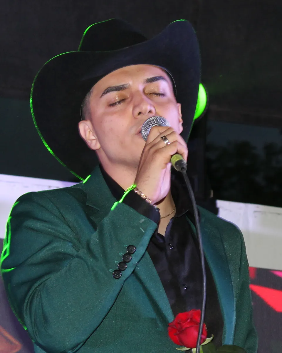 Alonso Guezt cantando en primer plano, con sombrero y traje verde